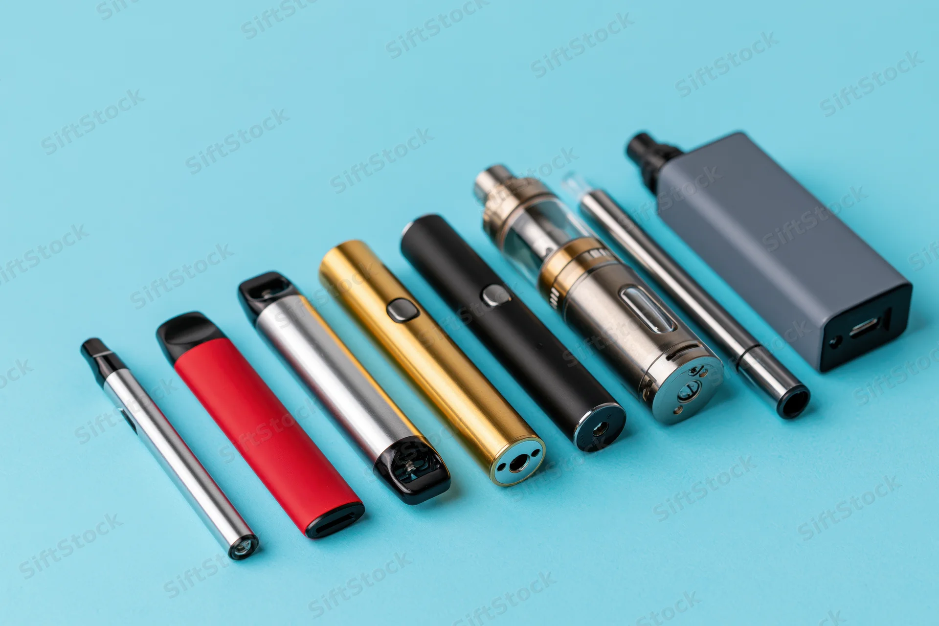 Various vaping devices and e-cigarettes arranged in a loose diagonal line on a blue background