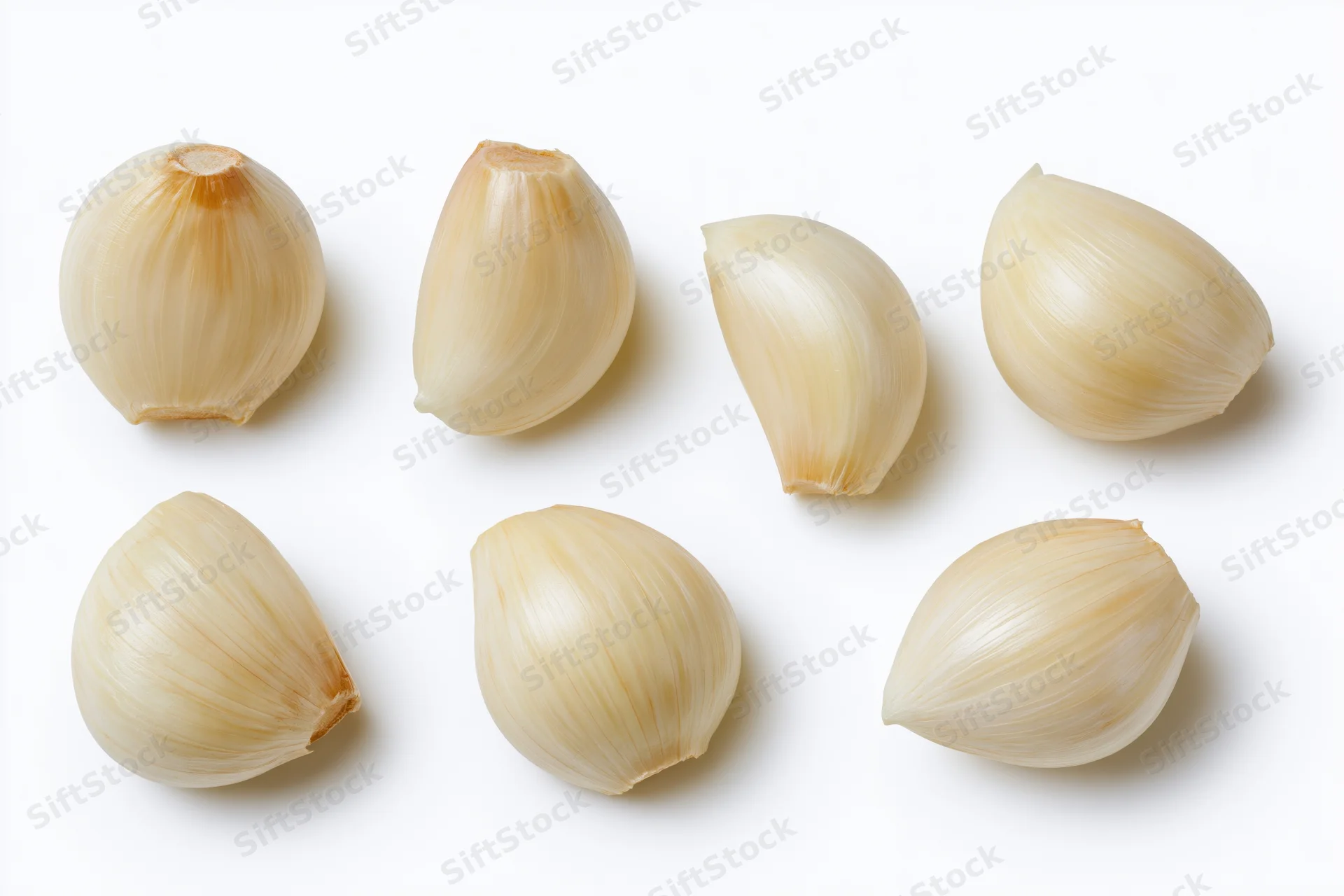 Six peeled garlic cloves arranged in two rows on a white background