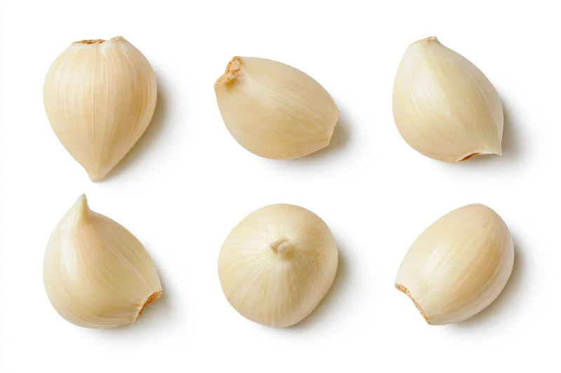 Six peeled garlic cloves arranged in two rows on a white background