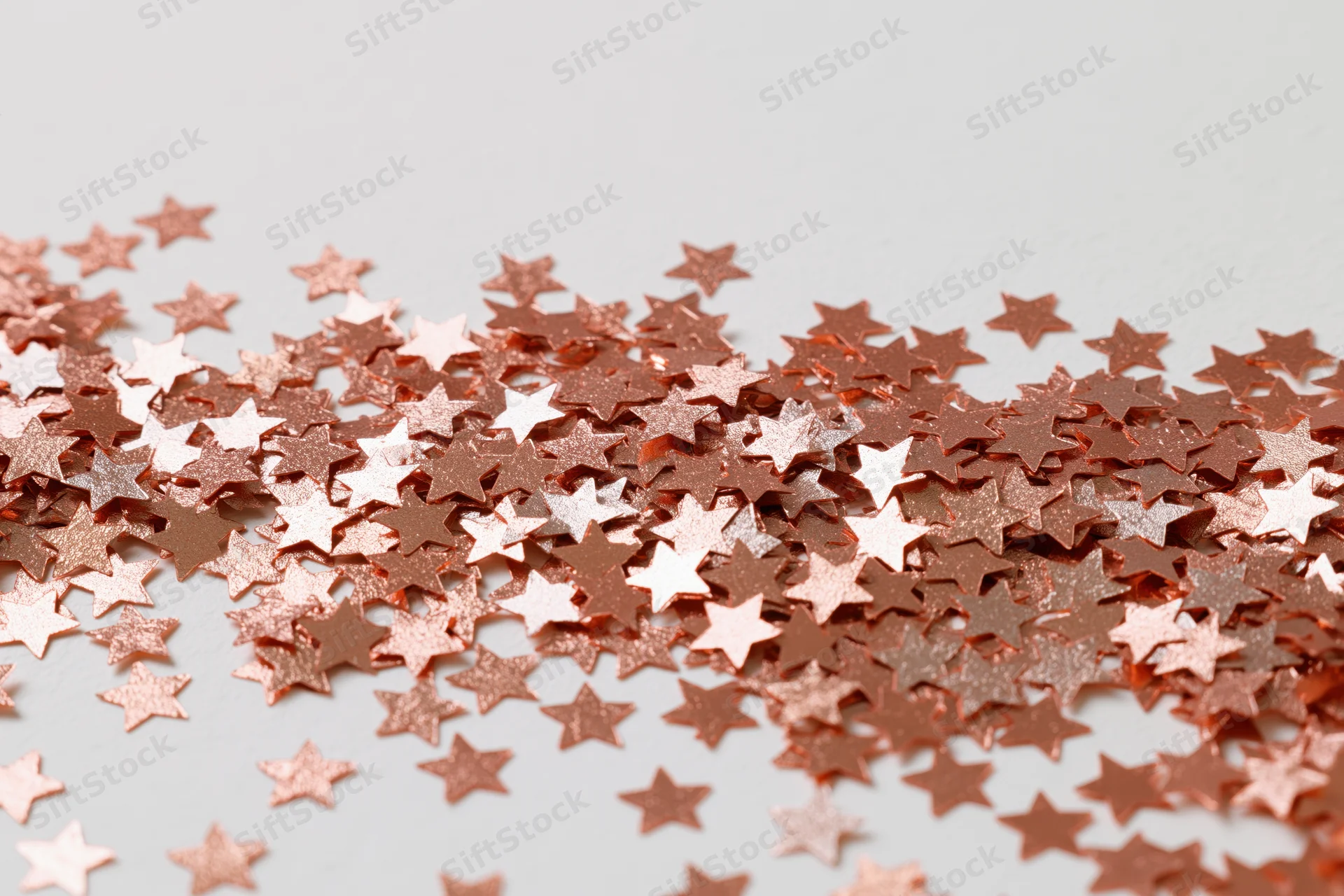 Metallic star-shaped confetti scattered across a white surface