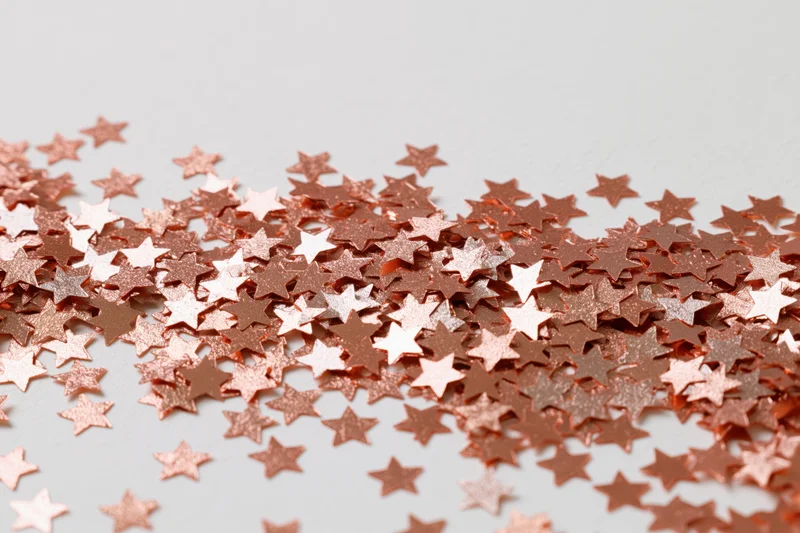 Metallic star-shaped confetti scattered across a white surface