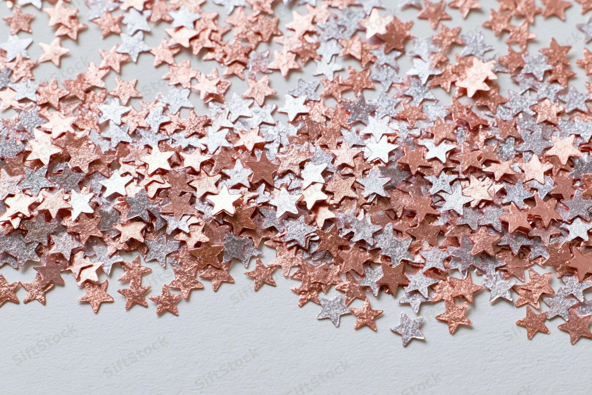 Metallic star-shaped confetti scattered across a white surface in a flat lay arrangement