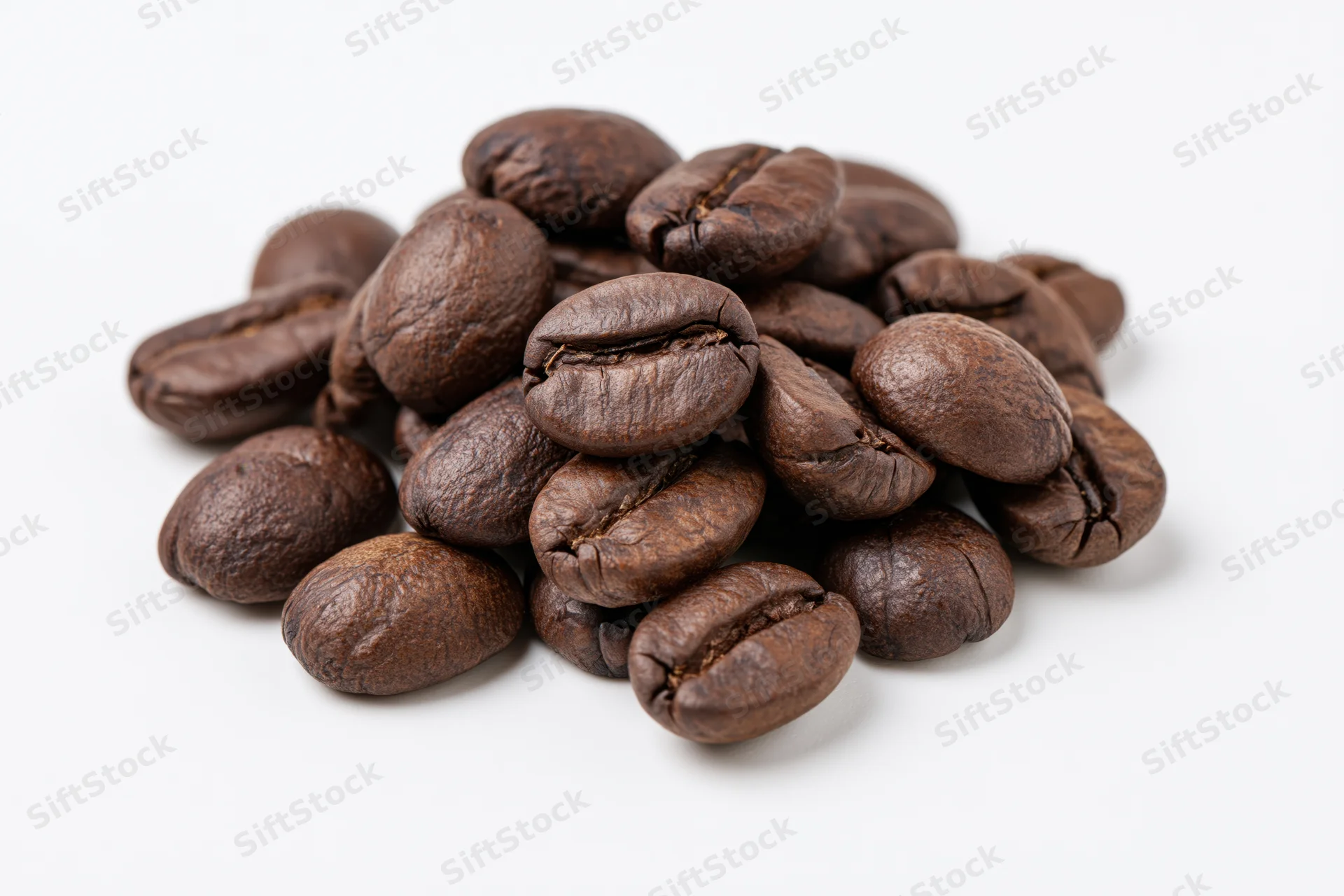 Small pile of roasted coffee beans resting on a flat white surface