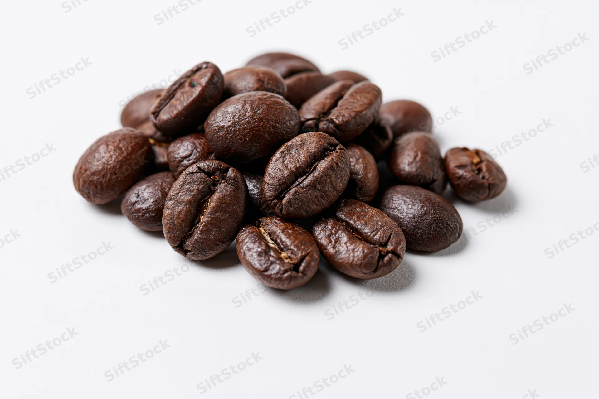 Small pile of roasted coffee beans resting on a flat white surface