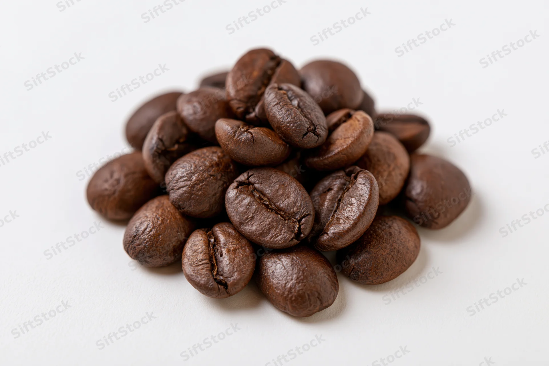 Small pile of roasted coffee beans resting on a flat white surface