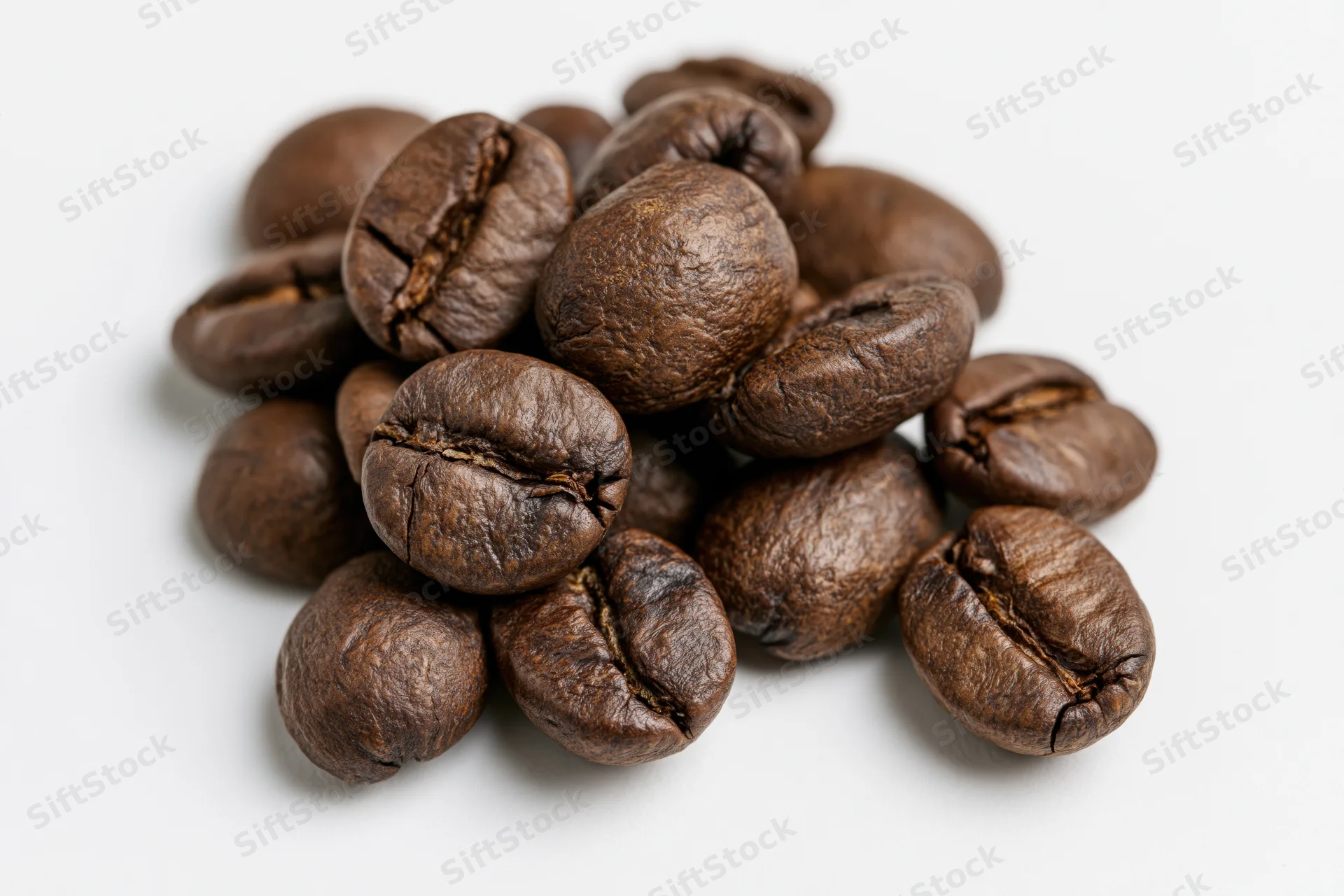 Roasted coffee beans piled on a flat white surface