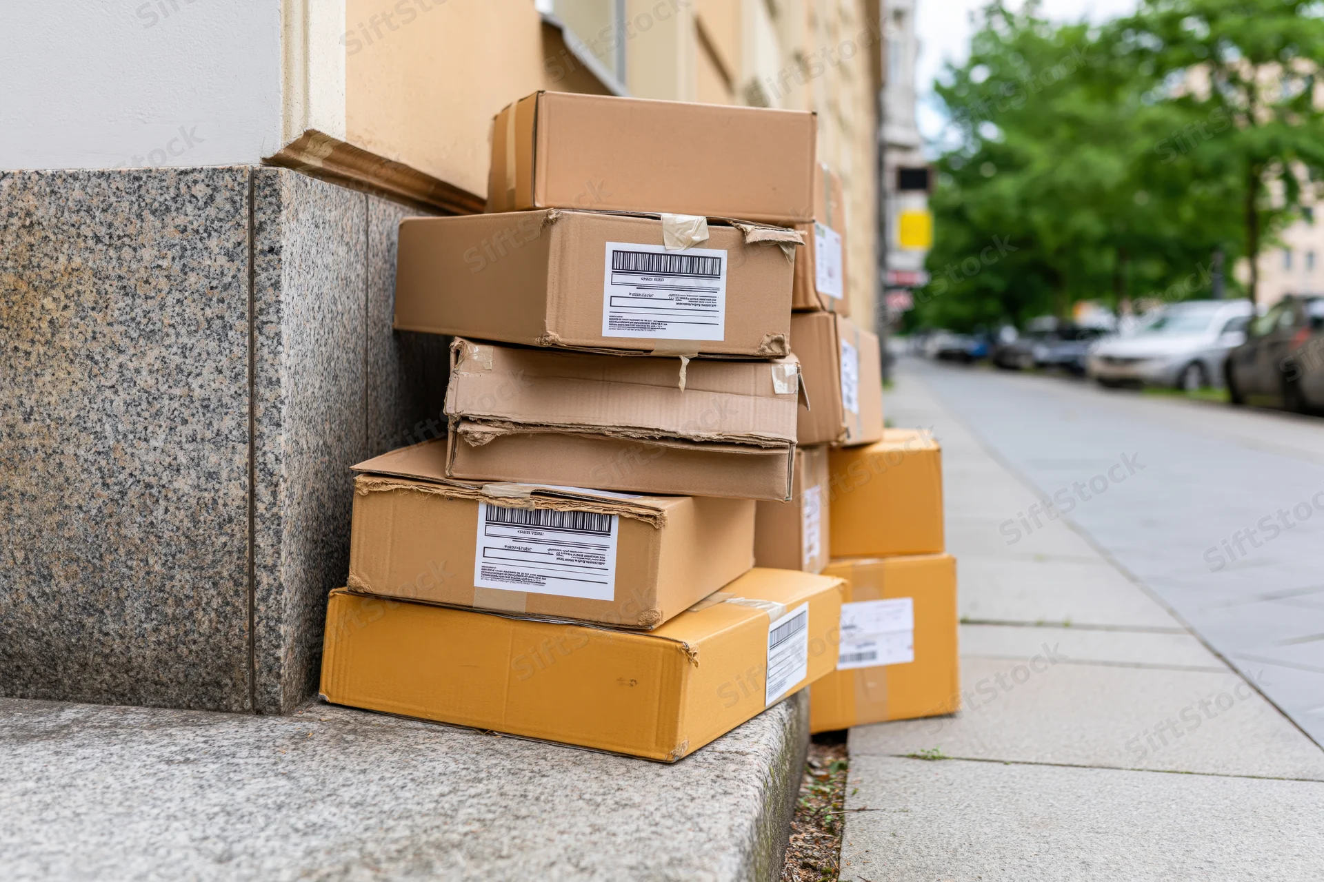 Stack of cardboard shipping boxes piled on city sidewalk steps