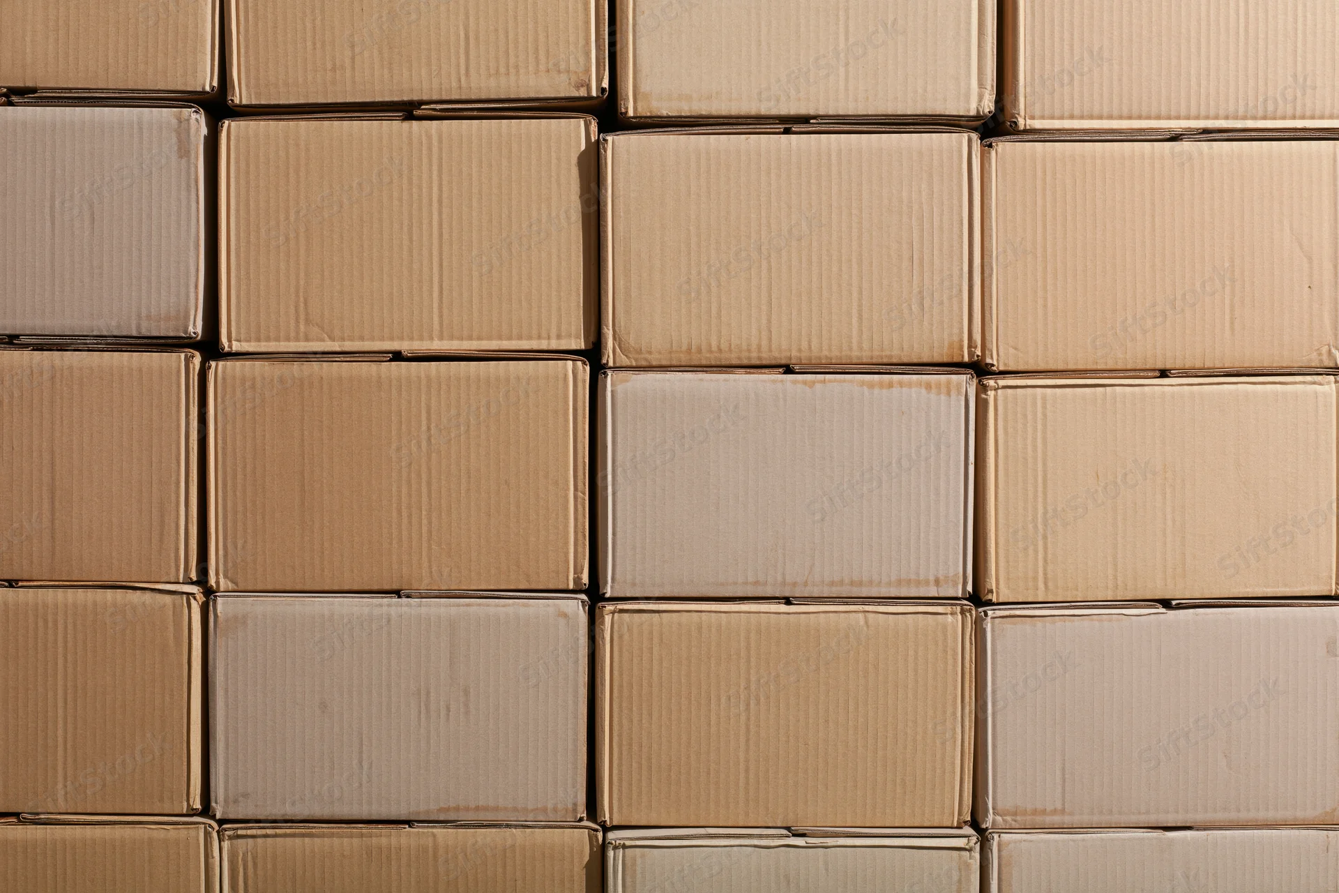 Stacked rows of sealed cardboard shipping boxes arranged in a grid pattern in a warehouse storage area