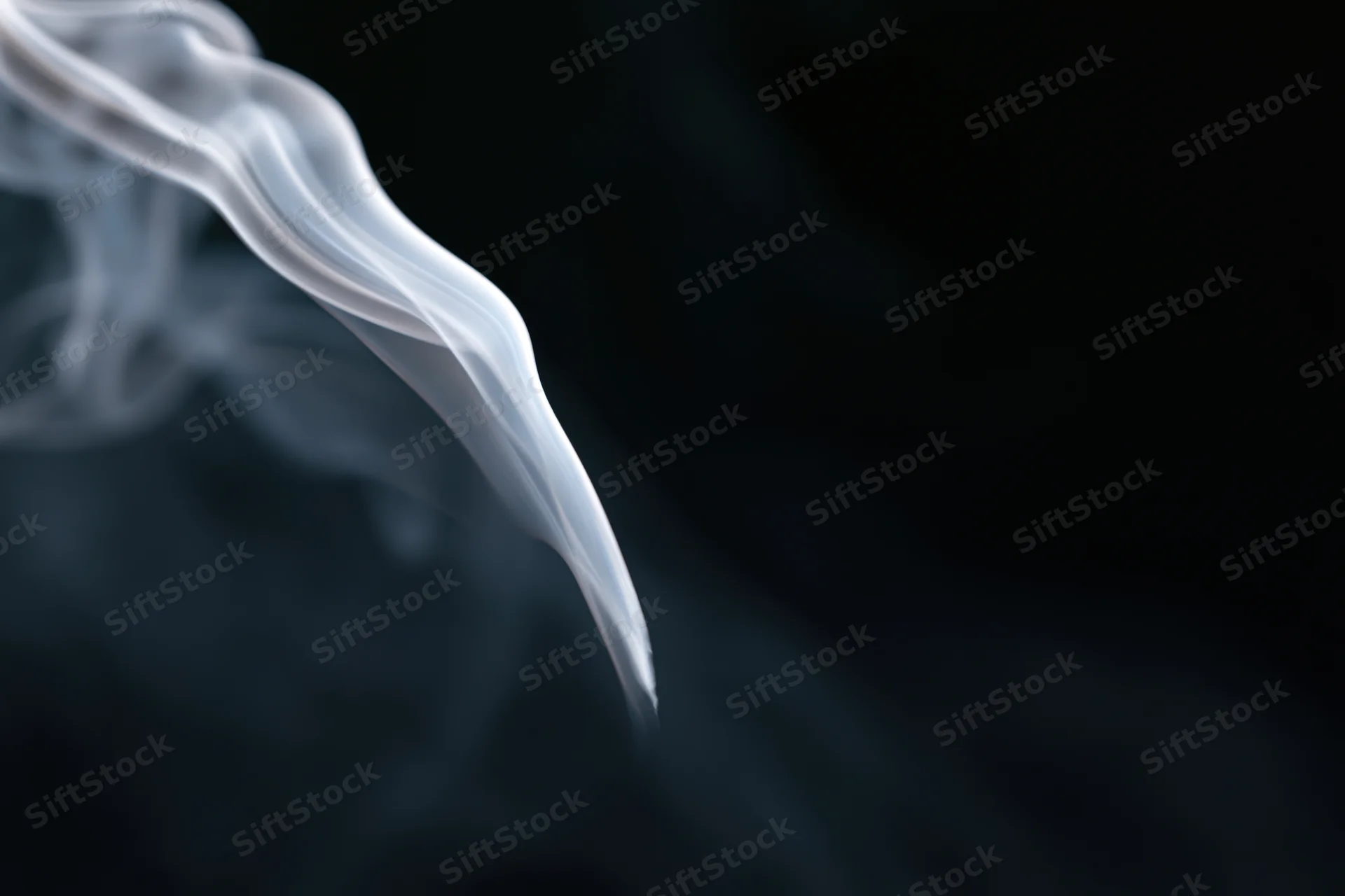 Thin wisp of white smoke curling upward against a dark background