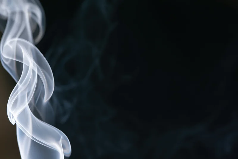 Thin white smoke curling upward against a dark background
