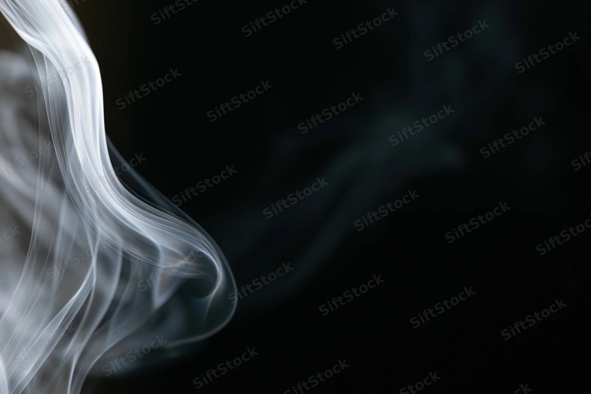 Thin wisp of white smoke curling upward against a dark background