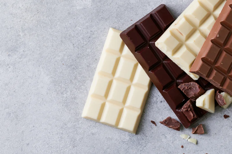 Three chocolate bars dark milk and white arranged overlapping on gray surface