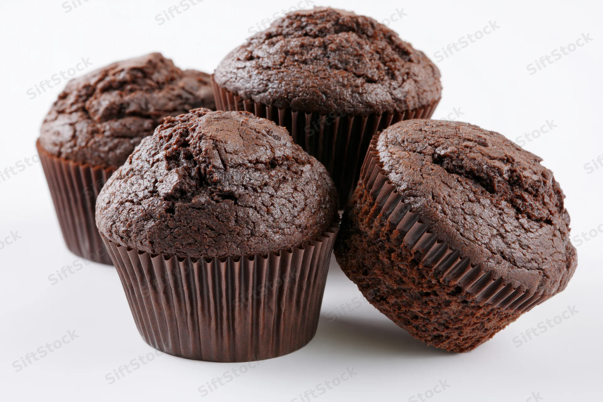 Chocolate muffins arranged in a loose stack against a plain white background