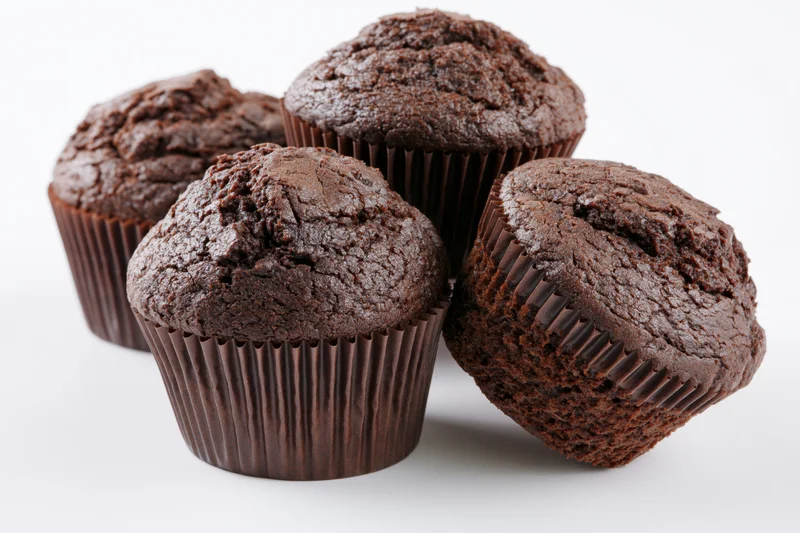 Chocolate muffins arranged in a loose stack against a plain white background