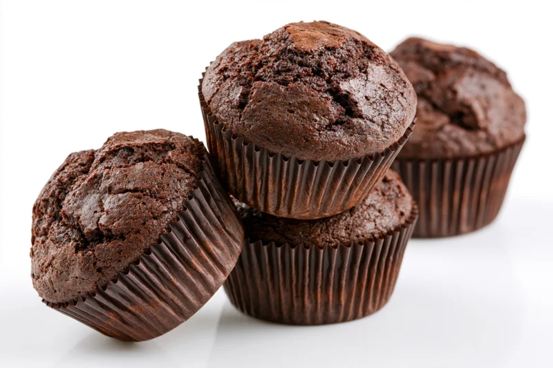 Chocolate muffins stacked and leaning on white background