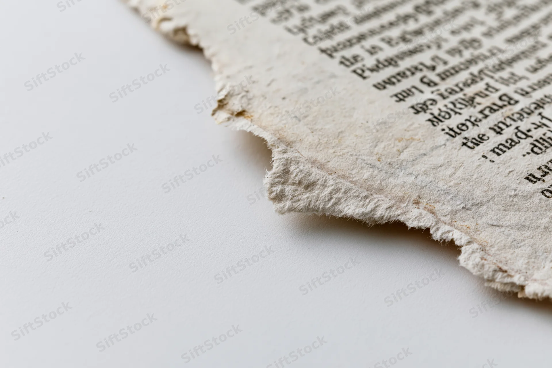 Torn aged newsprint fragment with printed text on white background