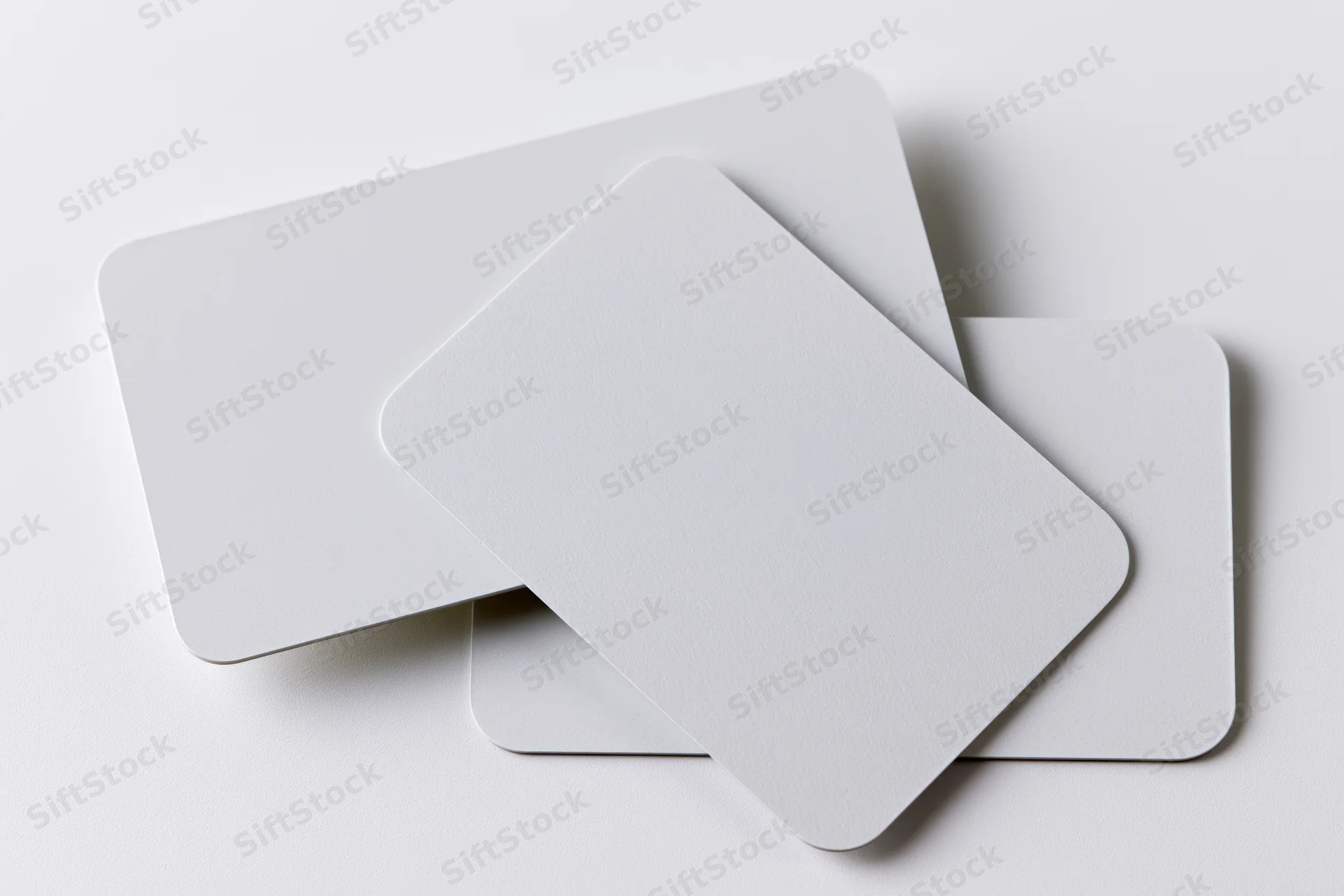 Three blank white business cards with rounded corners stacked and overlapping on a plain white surface