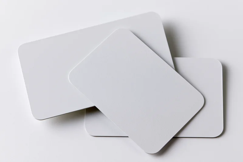Three blank white business cards with rounded corners stacked and overlapping on a plain white surface