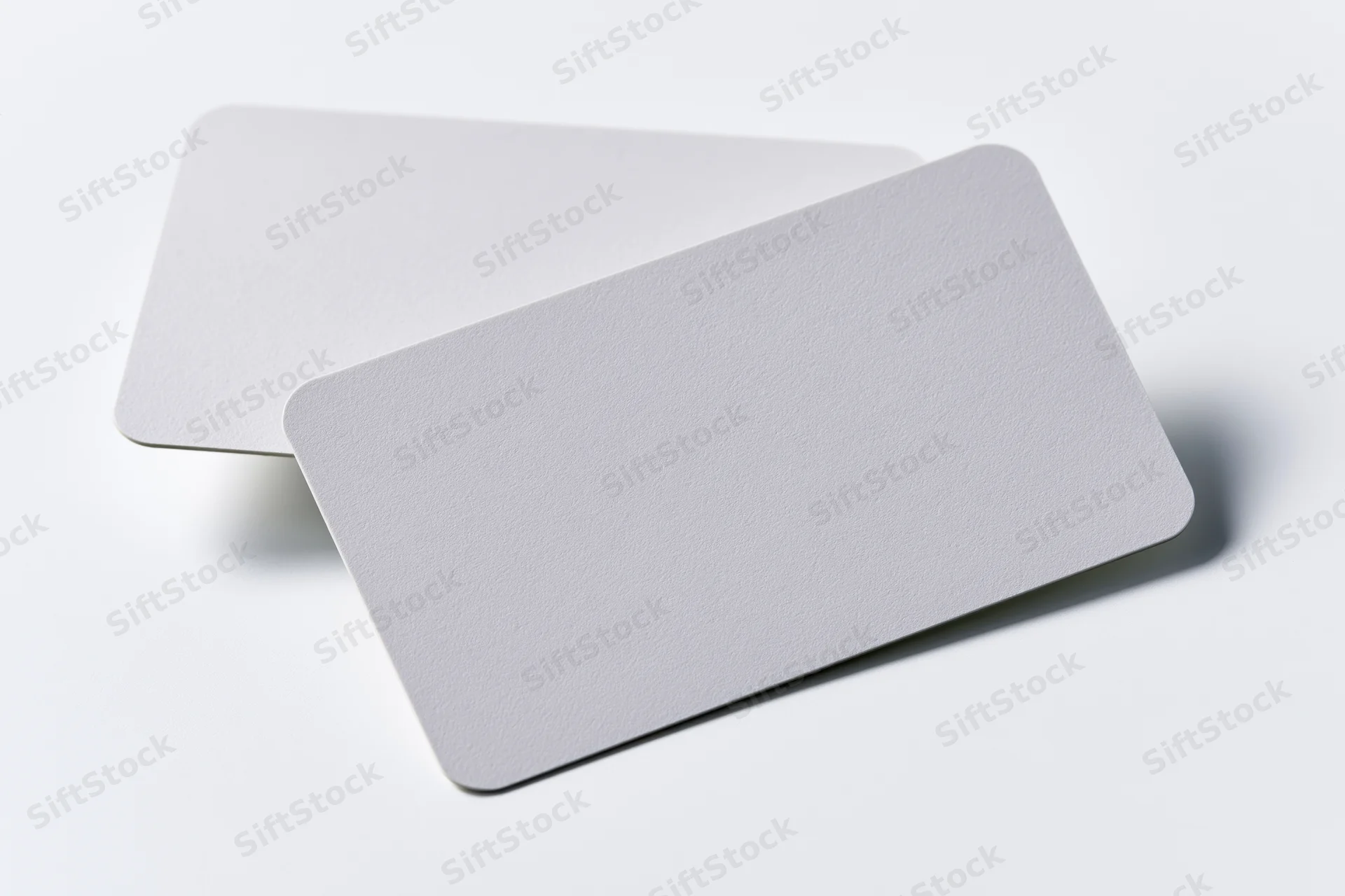 Two blank white business cards with rounded corners arranged overlapping on a white surface