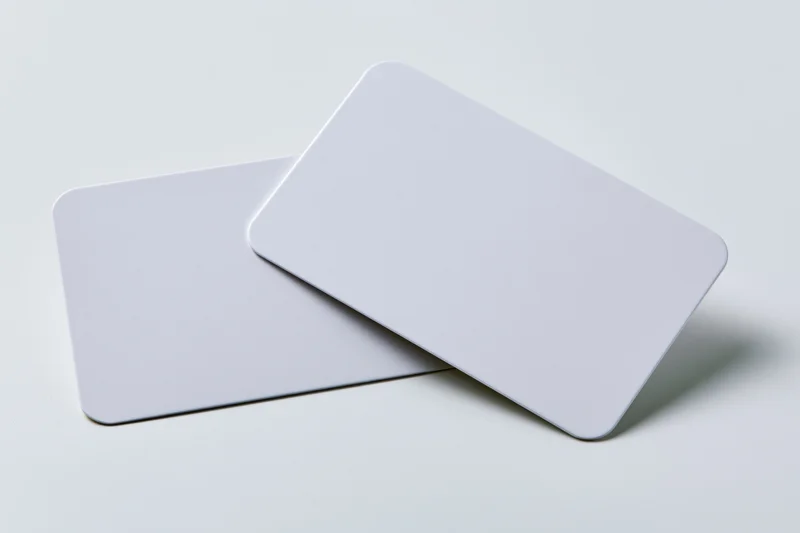 Two blank white business cards with rounded corners overlapping on a plain surface