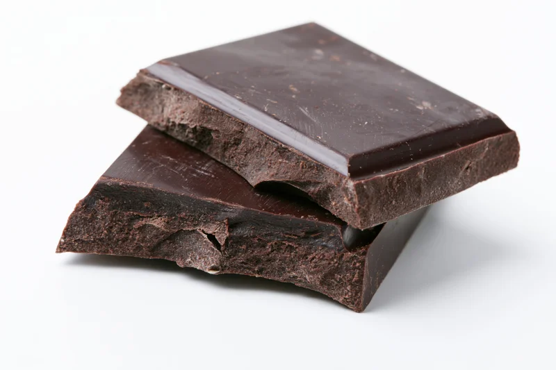 Two broken dark chocolate squares stacked slightly offset on white background