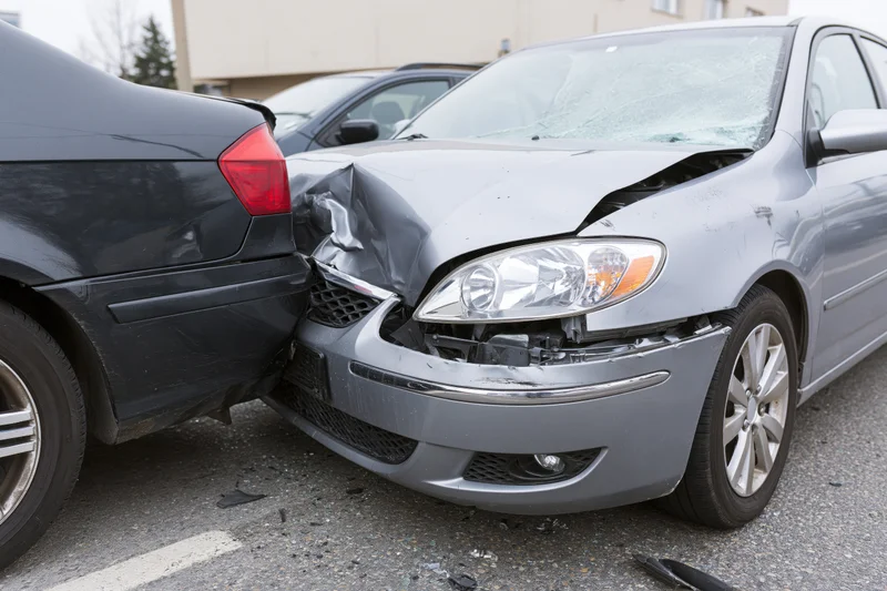 Two cars collided front-end in a parking lot on an urban street
