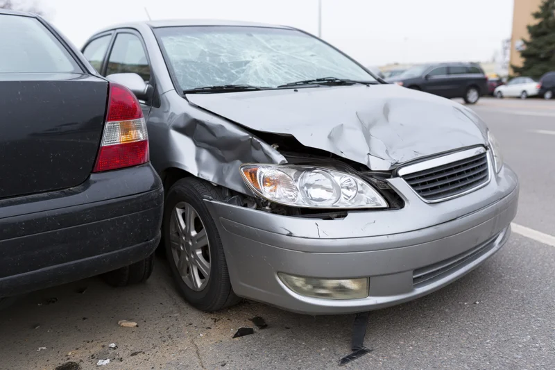 Two cars involved in a front-end collision in a parking lot on an urban street