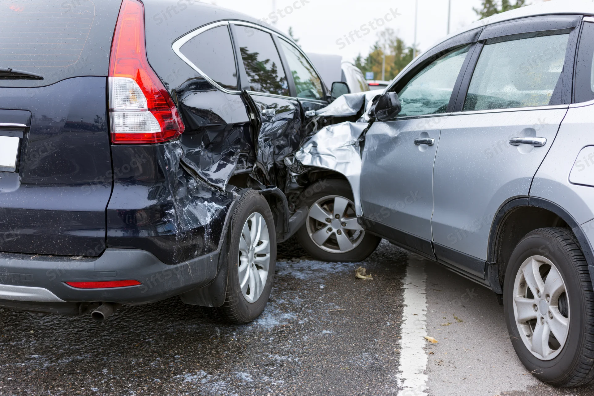 Two cars involved in a rear-end collision on a roadside with visible damage to bumpers and sides