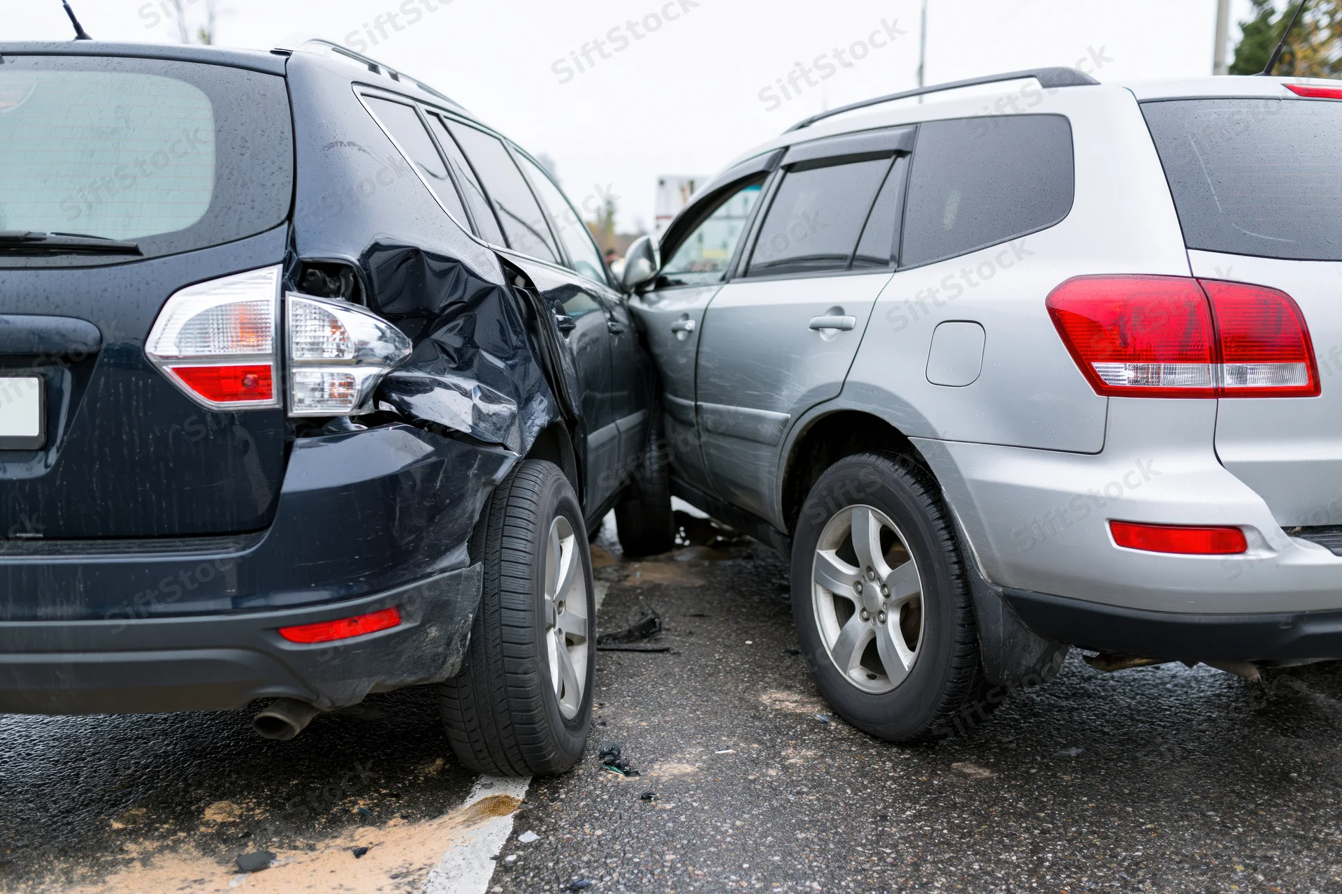 Two suvs involved in a rear-end collision on a wet roadside asphalt surface