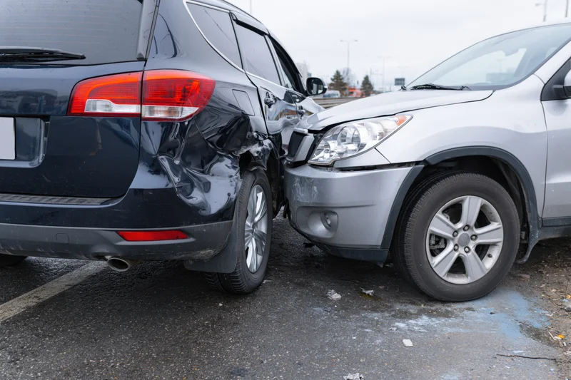 Two cars involved in a rear-end collision on a roadside parking area