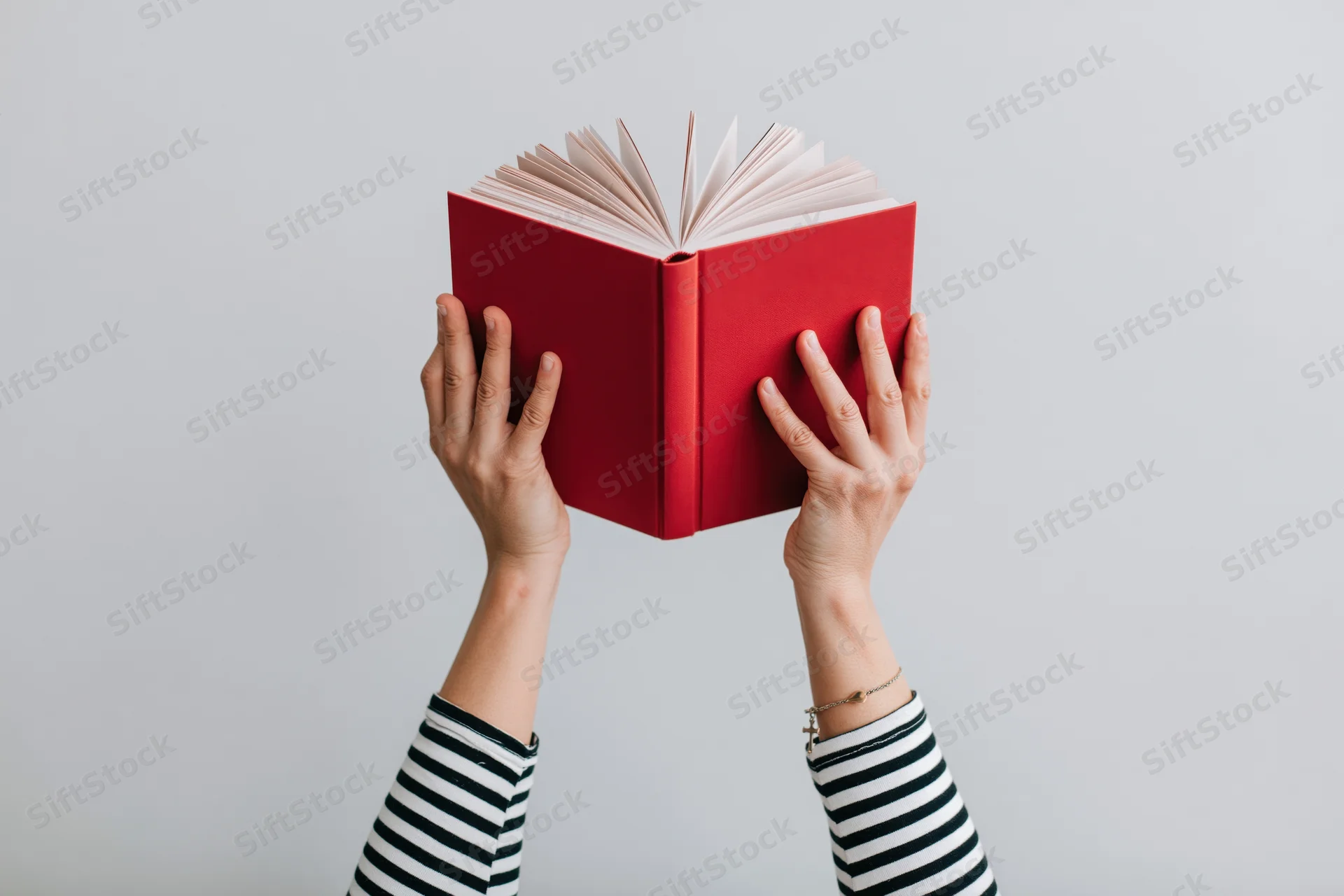 Hands holding open red hardcover book against white background