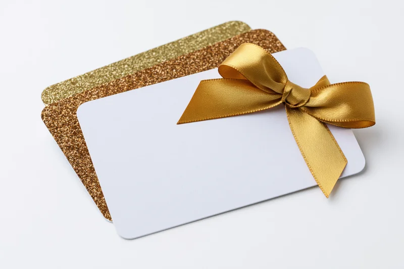 Two stacked gift cards with a gold ribbon bow on a white background