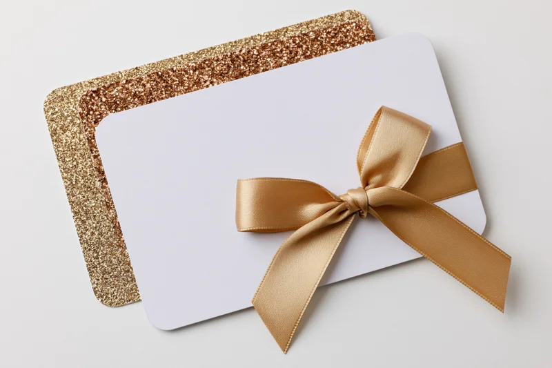 Two stacked gift cards with gold ribbon bow on white background