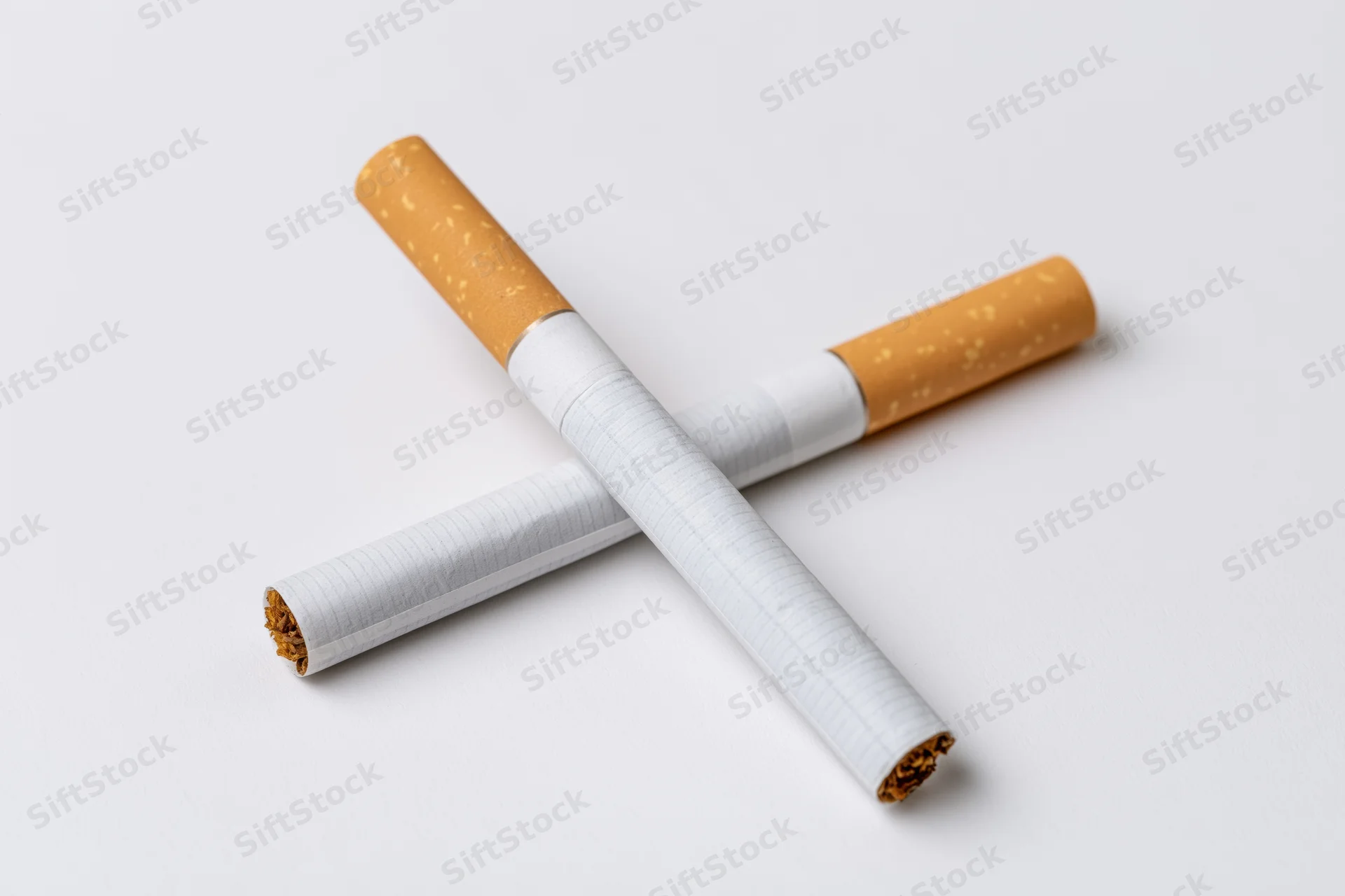 Two unlit cigarettes crossed on a plain white surface