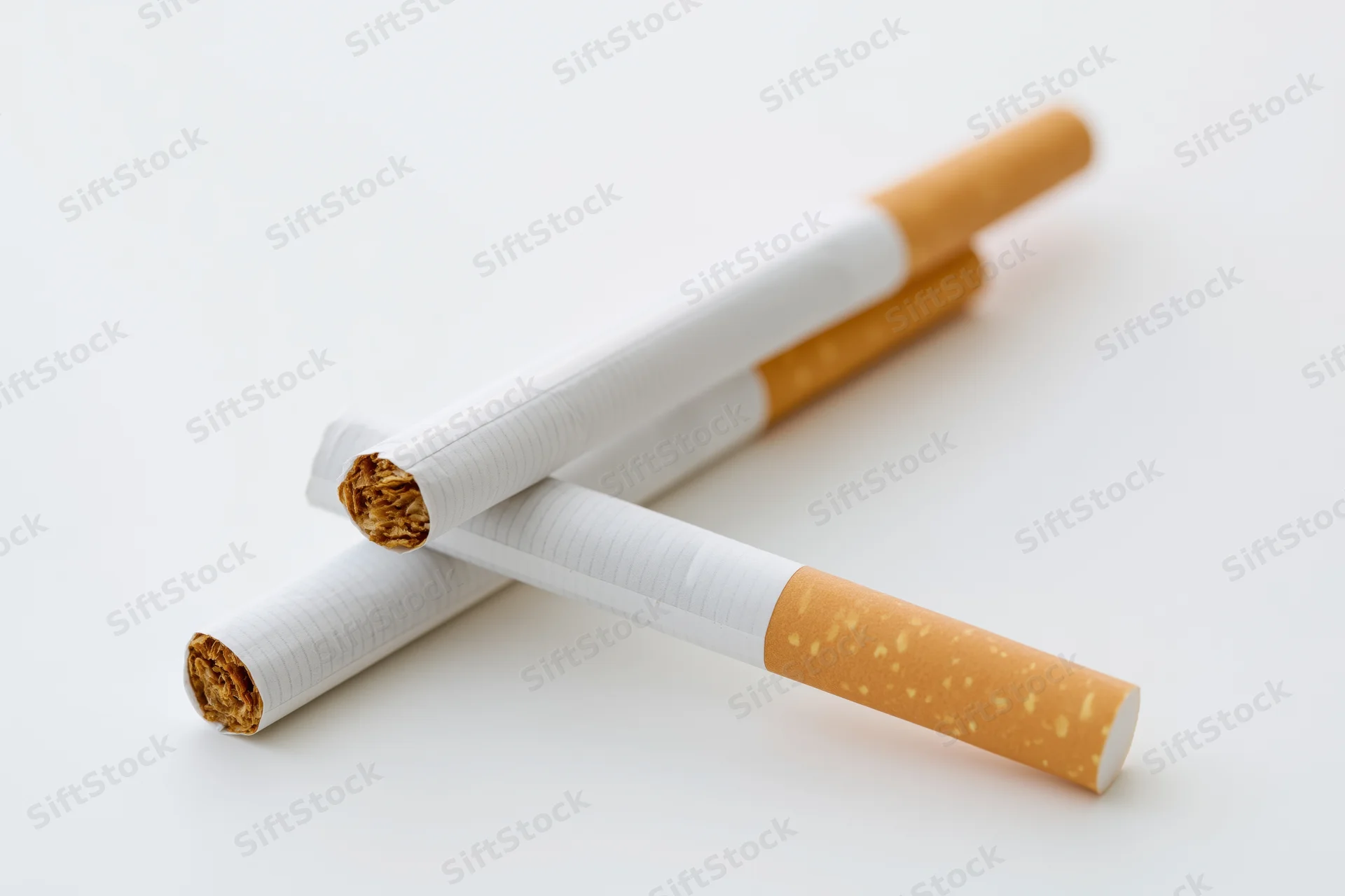 Two unlit cigarettes crossed on a plain white surface