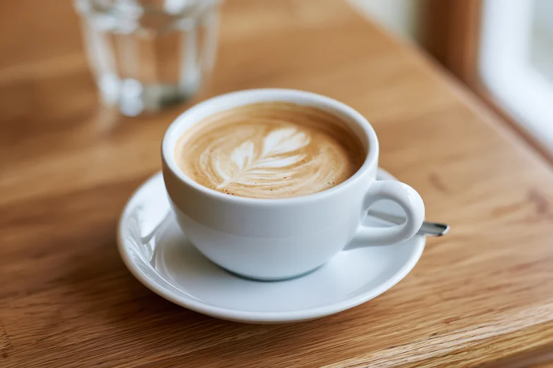 White ceramic cappuccino cup on a white saucer with a spoon