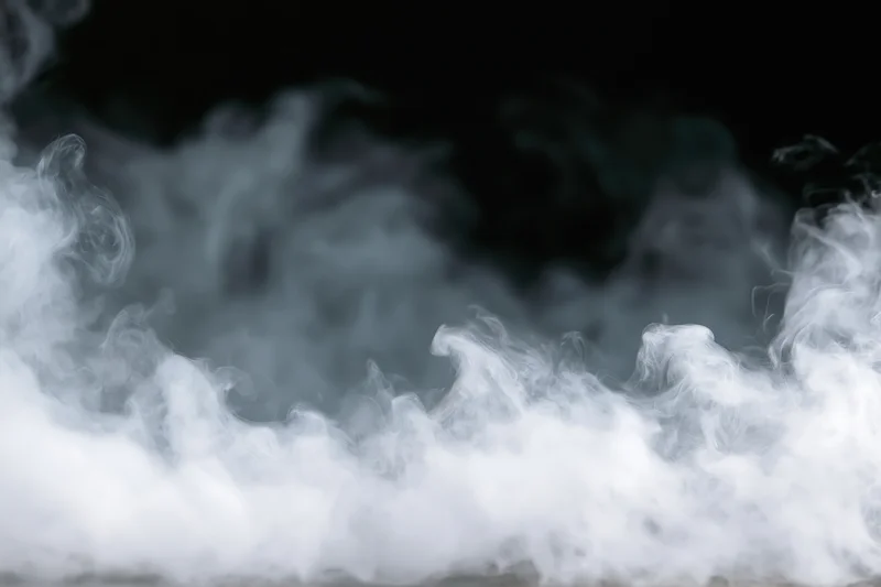 White smoke and mist drifting along the bottom and sides against a black background