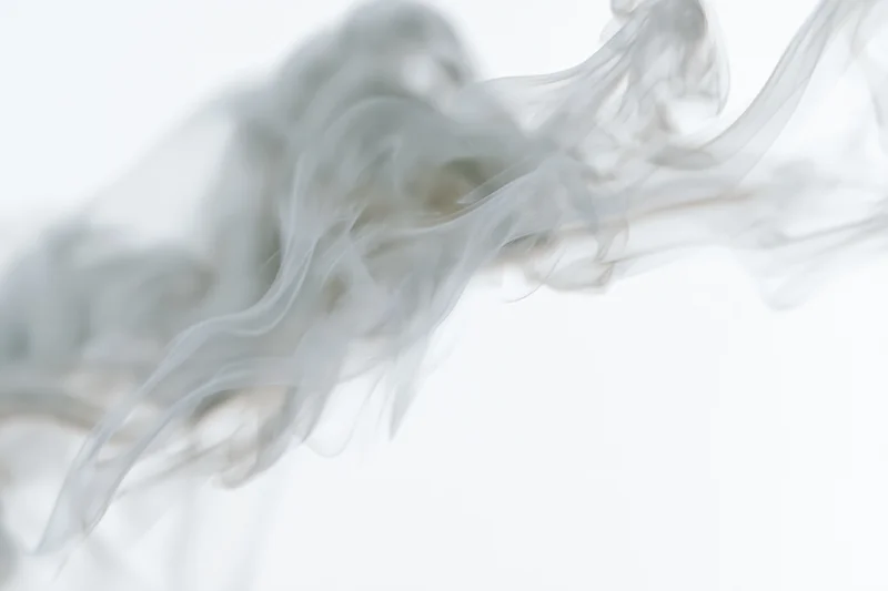 Wispy smoke curling and dispersing in mid-air against a pure white background