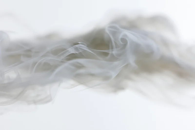 Wispy smoke drifting and dispersing against a plain white background