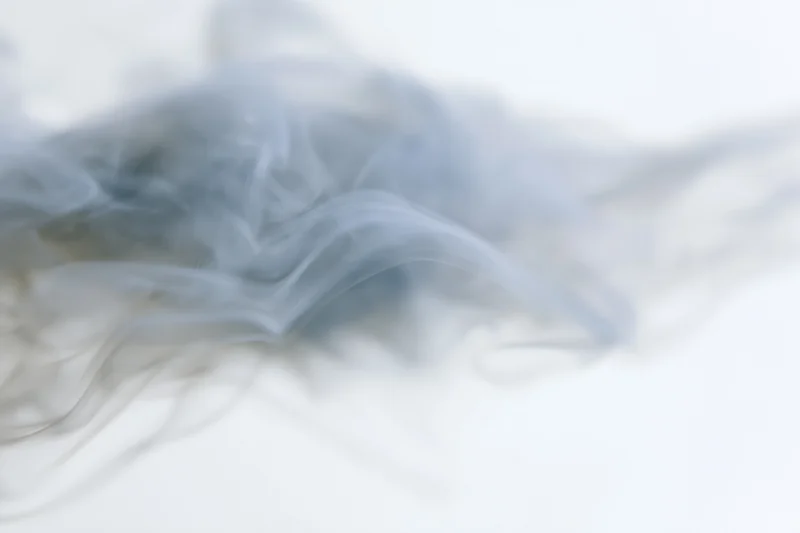 Wispy white smoke drifting and dispersing against a pure white background