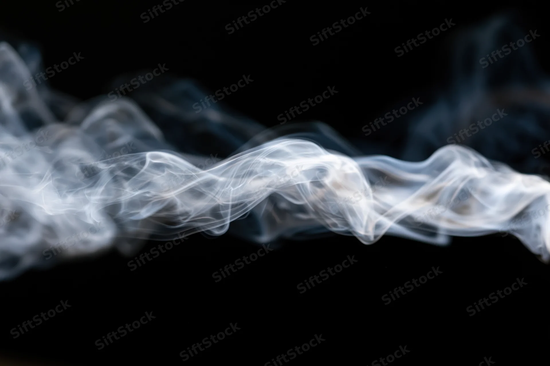 Wispy white smoke tendrils curling and dispersing mid-air against black background