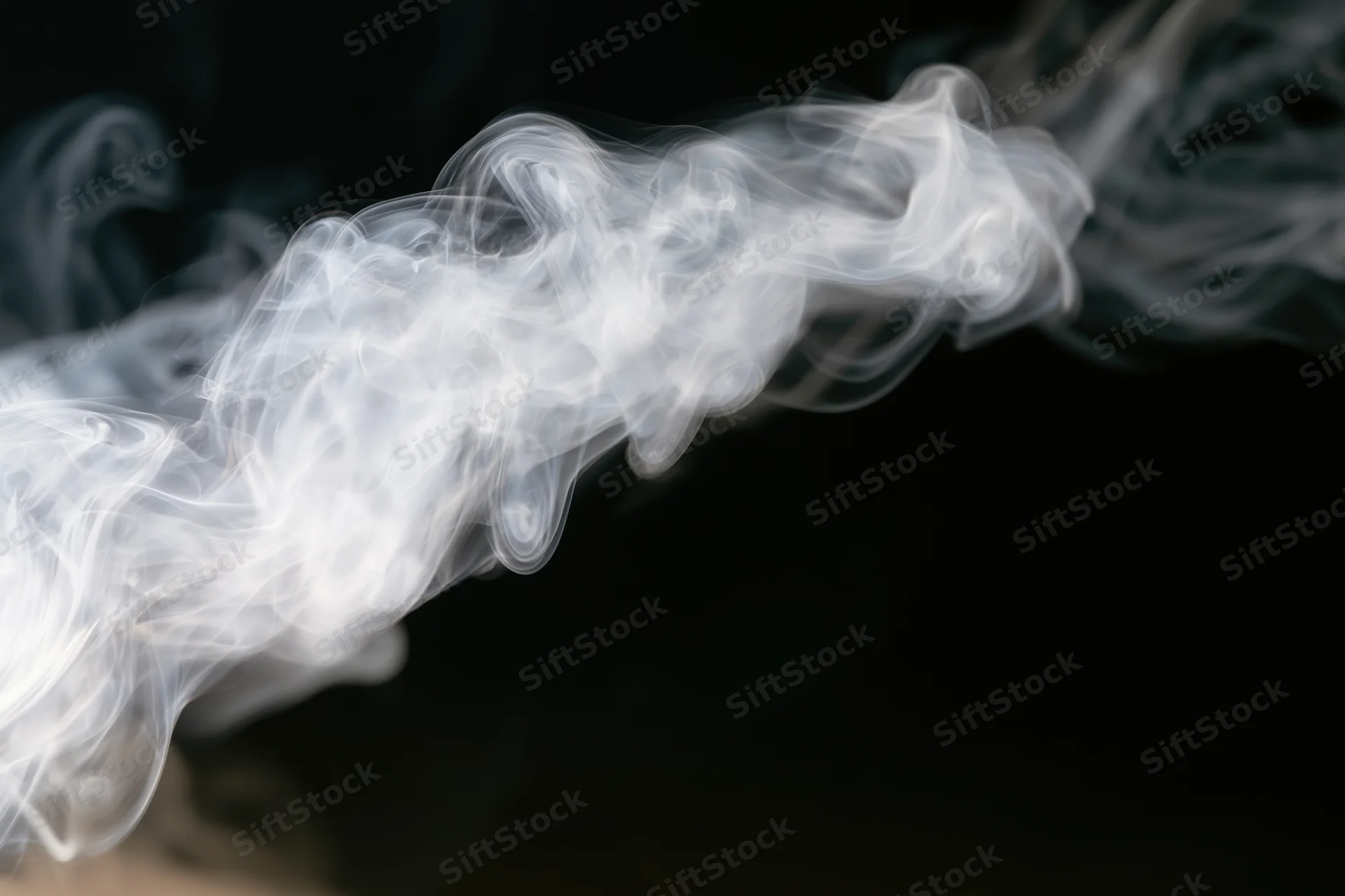 White smoke tendrils curling and dispersing mid-air against black background