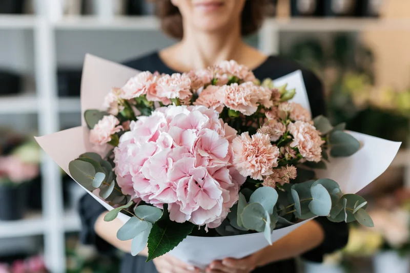 Woman holding a large bouquet of pink hydrangeas and carnations with eucalyptus in a flower shop