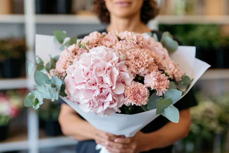 Woman holding a large bouquet of blush pink hyacinths and carnations with eucalyptus in a flower shop