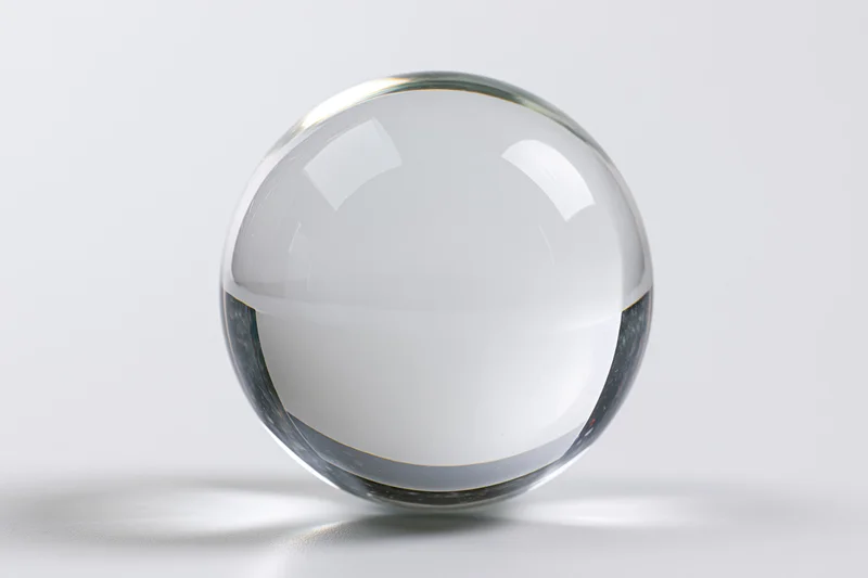 Clear glass crystal sphere resting upright on a white surface