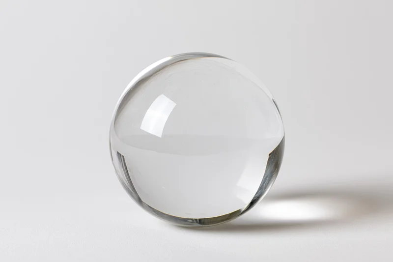 Clear glass crystal sphere resting upright on white surface