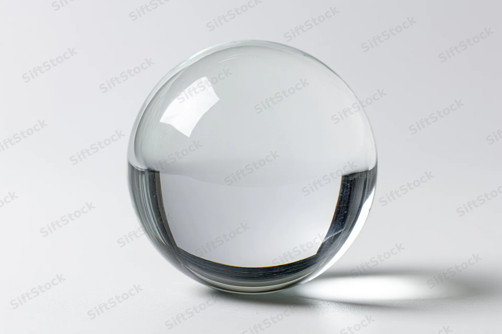 Clear glass sphere resting on plain white surface in studio setting