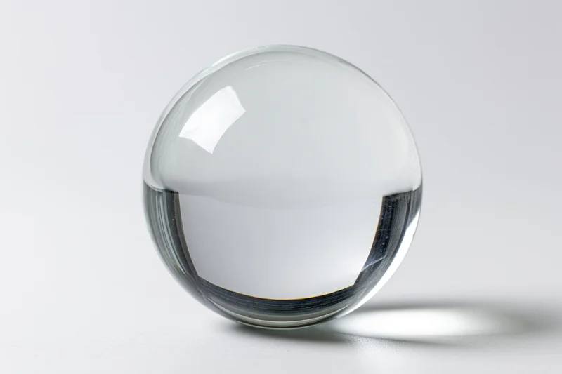 Clear glass sphere resting on plain white surface in studio setting