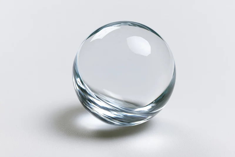 Clear glass sphere resting on plain white surface centered