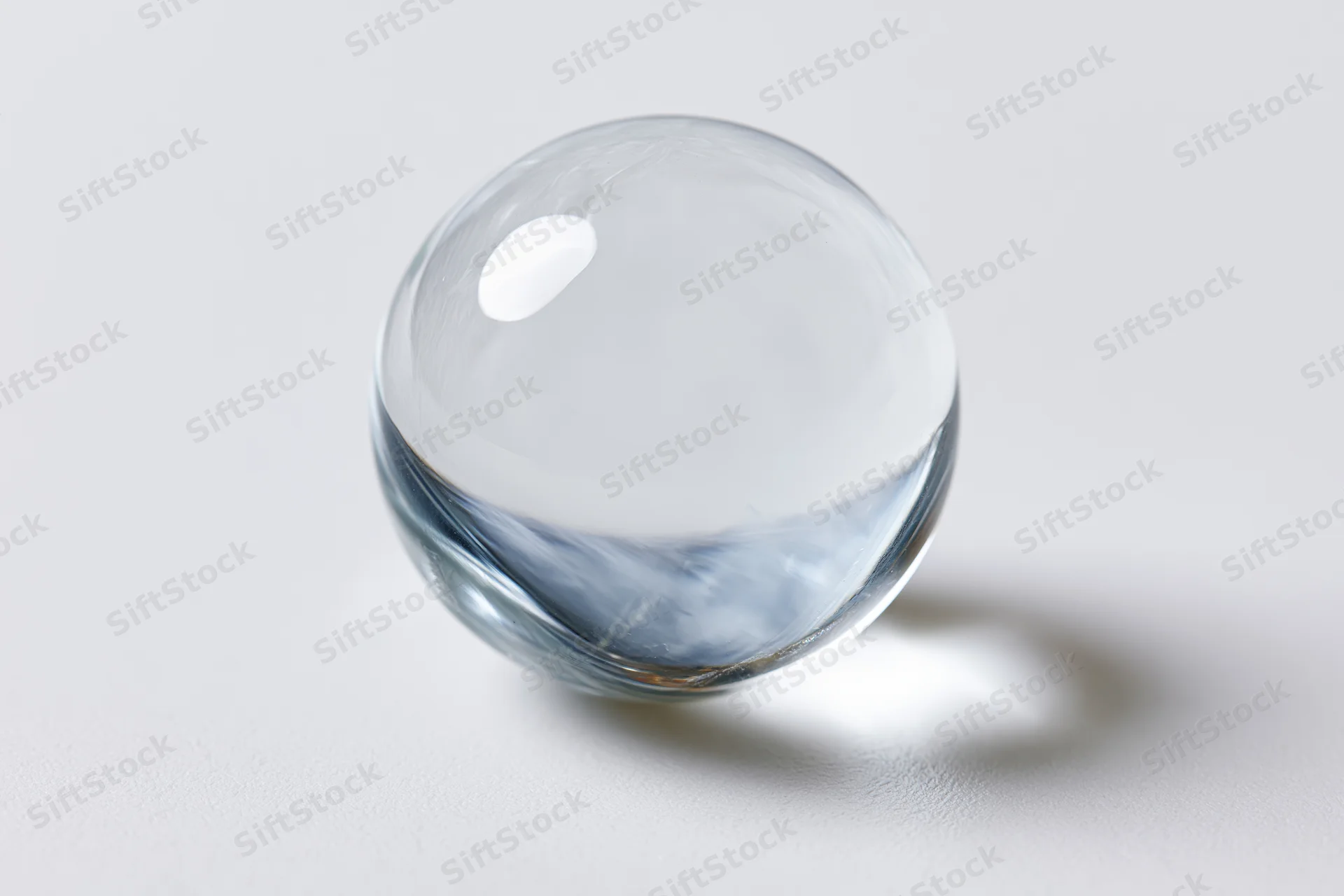 Clear glass sphere resting on plain white surface